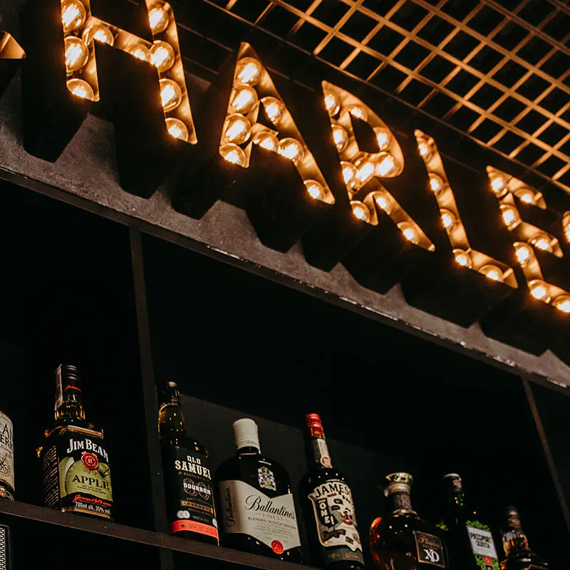 Marquee CHARLES & CO — żarówki w literach, półka z whisky